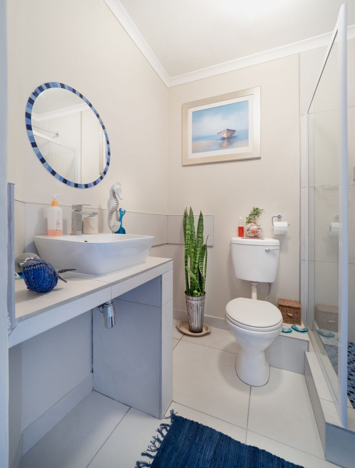 A real bathroom with a white toilet beside a glass shower enclosure and vanity