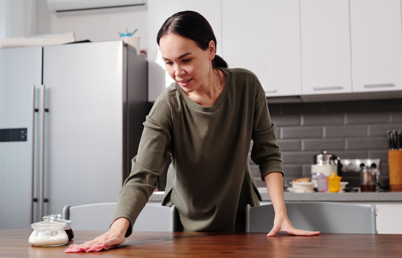 A person wiping a table with a cloth in a home kitchen.