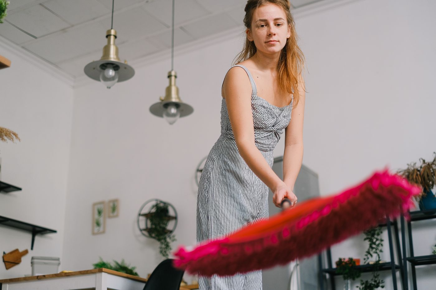 A woman holding a visibly textured red flat mop pad in a furnished interior.
