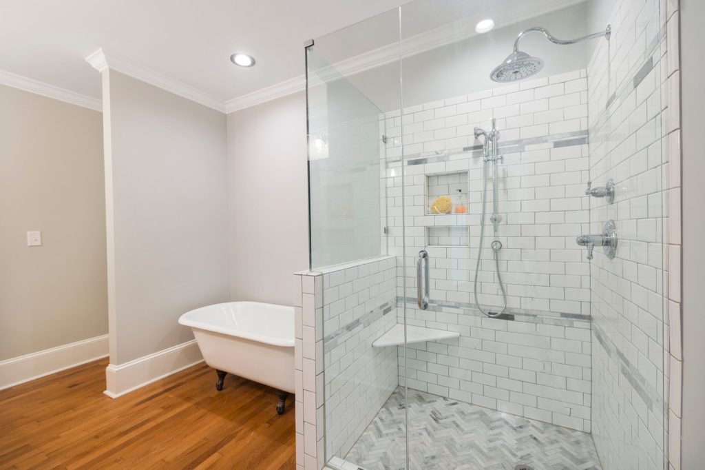 A residential bathroom with a glass shower enclosure and freestanding bathtub.